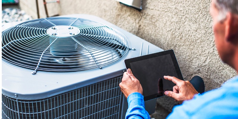 HVAC mechanic checking AC with digital tablet