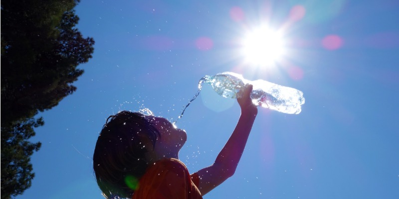 Young boy in the sun pours water on himself