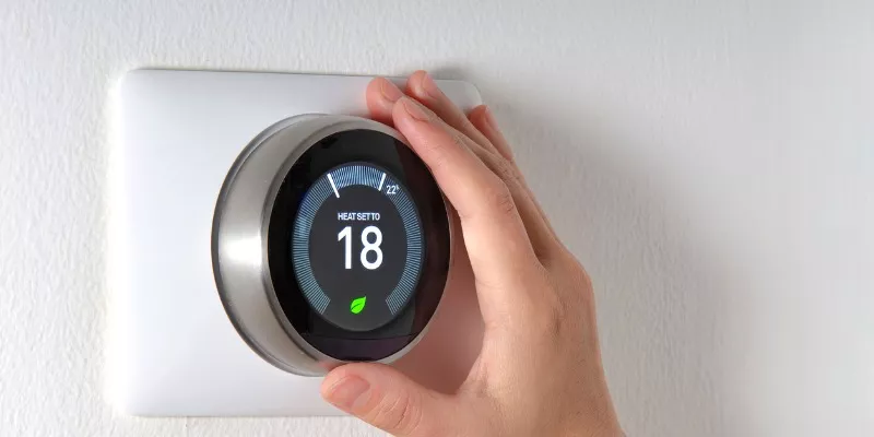 hand changing the temperature on a smart thermostat