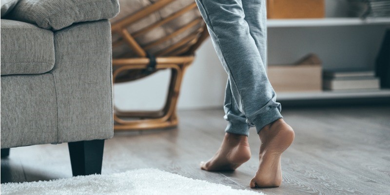 Lady walking on tip toes across wood floor