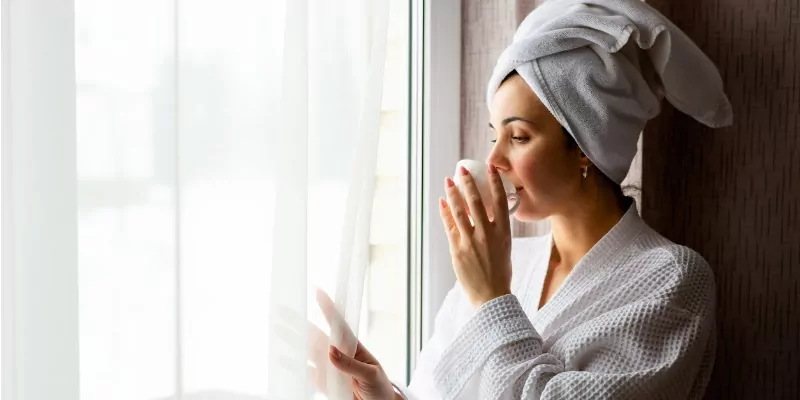 woman drinking coffee in robe after shower