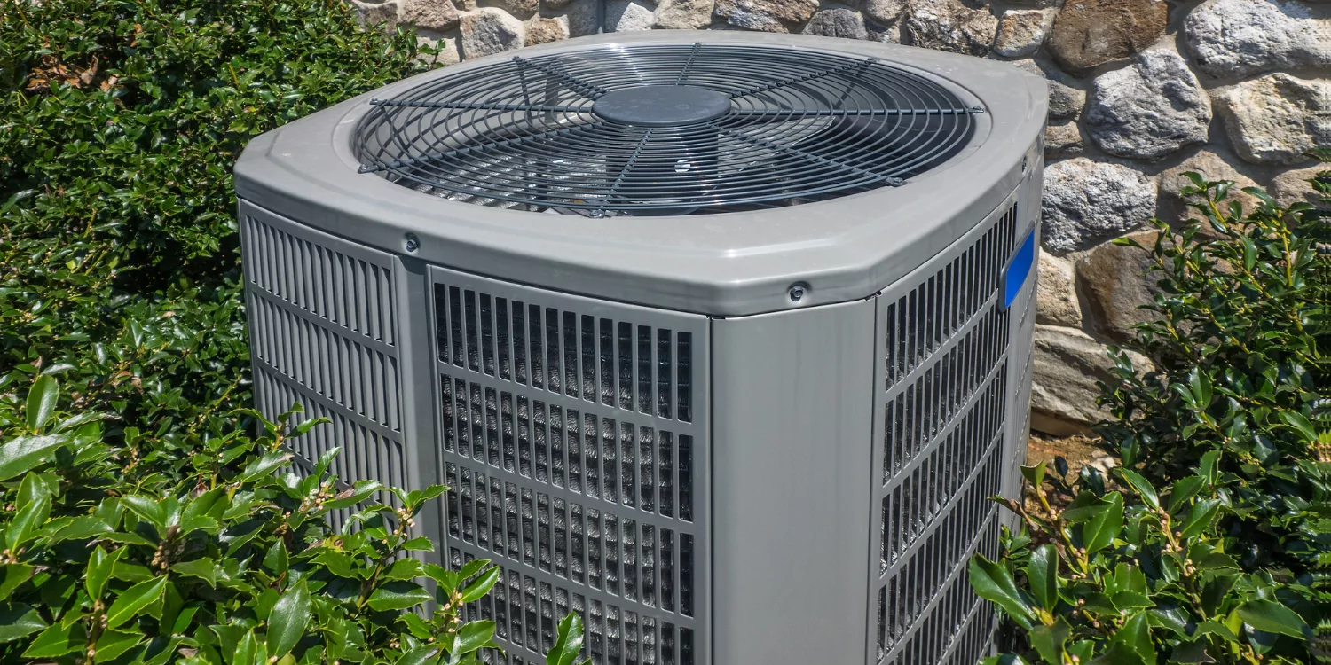 AC Unit surrounded by greenery - 5 Reasons Why 'Topping Off' Your AC Can Do More Harm Than Good