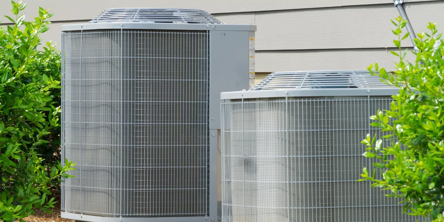 Two AC Units Outside of home near plants & shrubs - The 5 Signs It's Time to Upgrade Your AC Unit According to Experts 