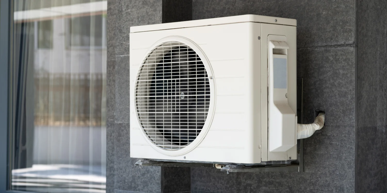 Heat Pump against grey home - Benefits of Air Source Heat Pumps: Efficiency, Cost Savings, Improved Comfort & More