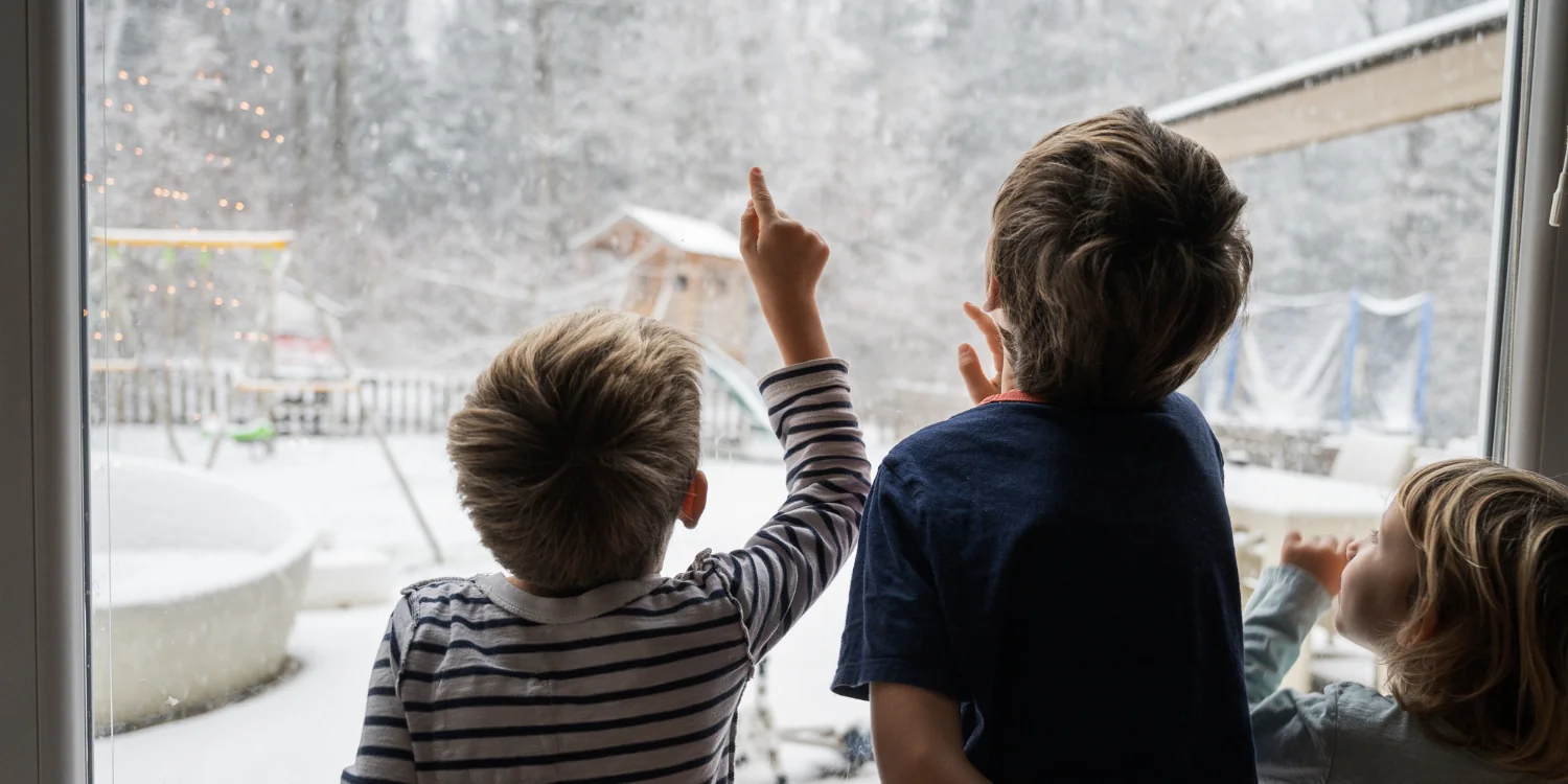 4 Reasons to Consider a Hybrid Heating System For Your Home Comfort - Three siblings looking out snowy window